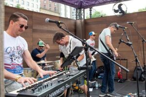 The Roland High Life — Walker Dieckmann (keyboards), Chris Correia (drums), Thom Dunn (guitar), Jake WM (bass), and Nick Krefting (guitar) — performing at the Emerson College Uncommon Stage in Boston, Massachusetts